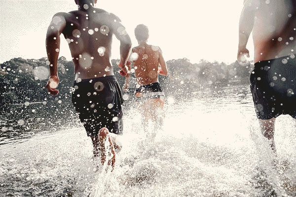 Friends running into the water at the beach using health supplements