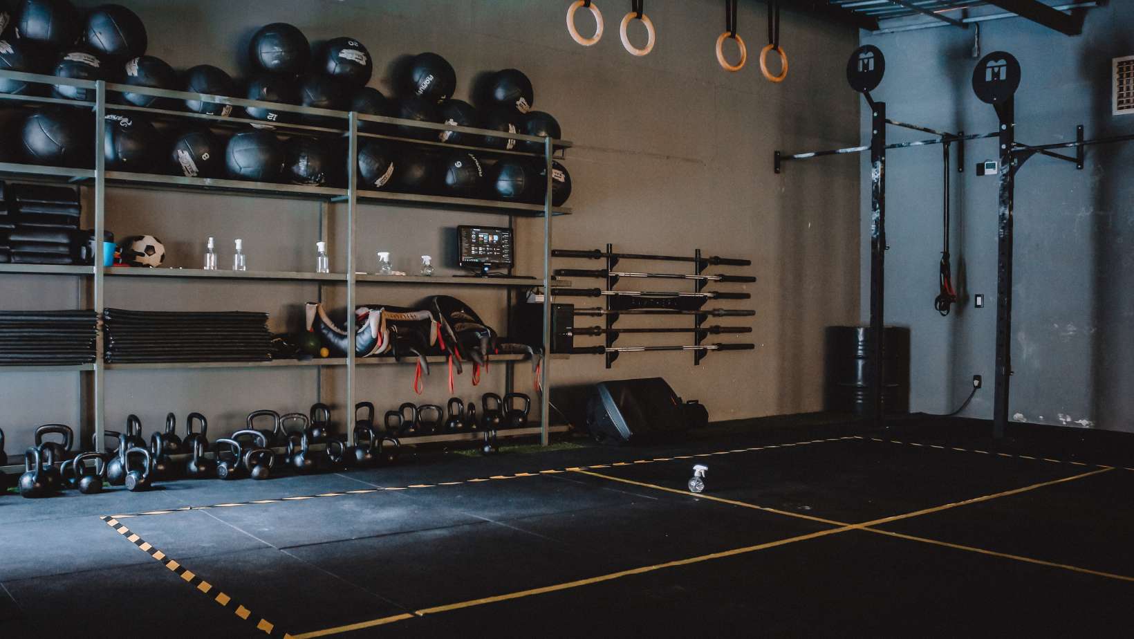 A CrossFit Box with Equipment on a Steel Shelves Near a Gymnastic Rings