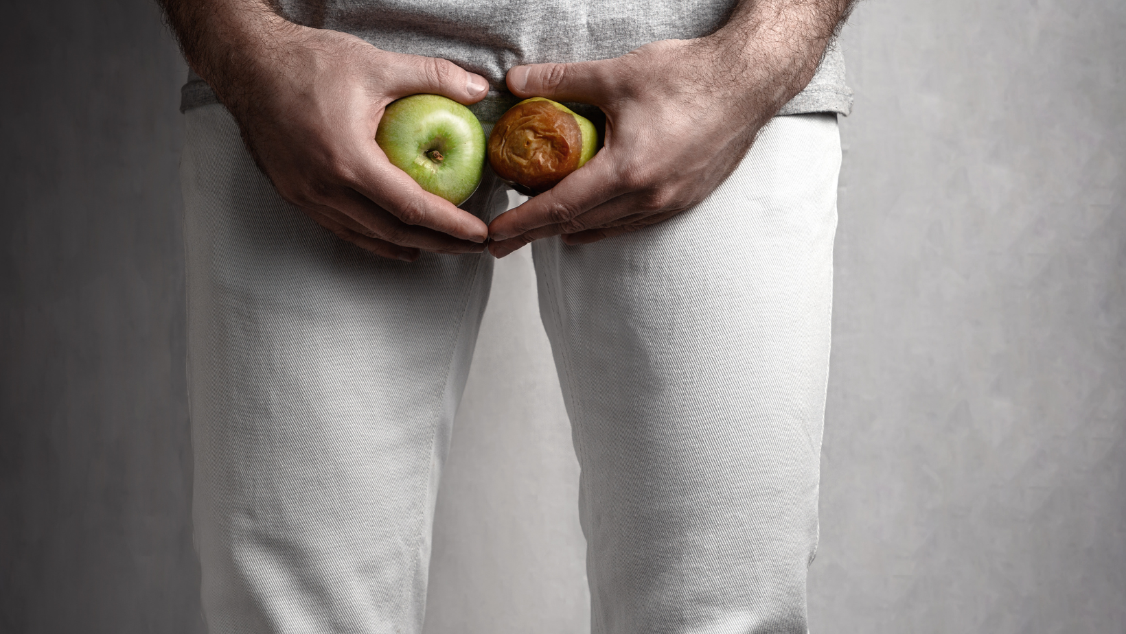 A Man  Holding a Ripe and Rotten Apple. The Concept of Protection of ejaculation. Close up