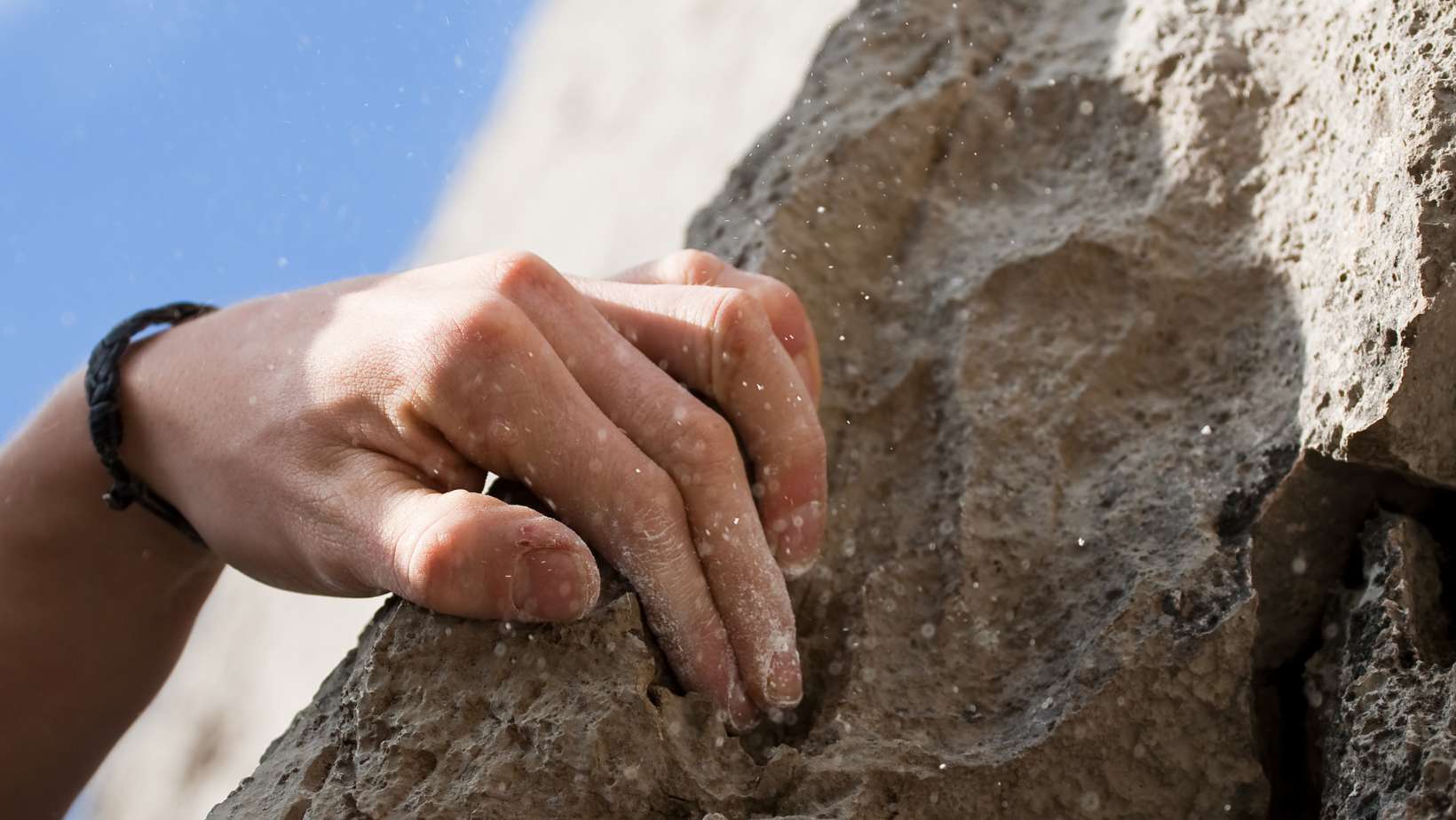 A climbers hand grips a rock edge