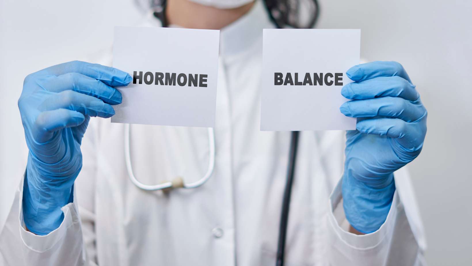 A female doctor holding two white cards with Hormone balance words. Hormone balance concept