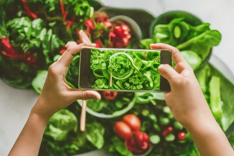 Woman photographing fresh green salad bowl