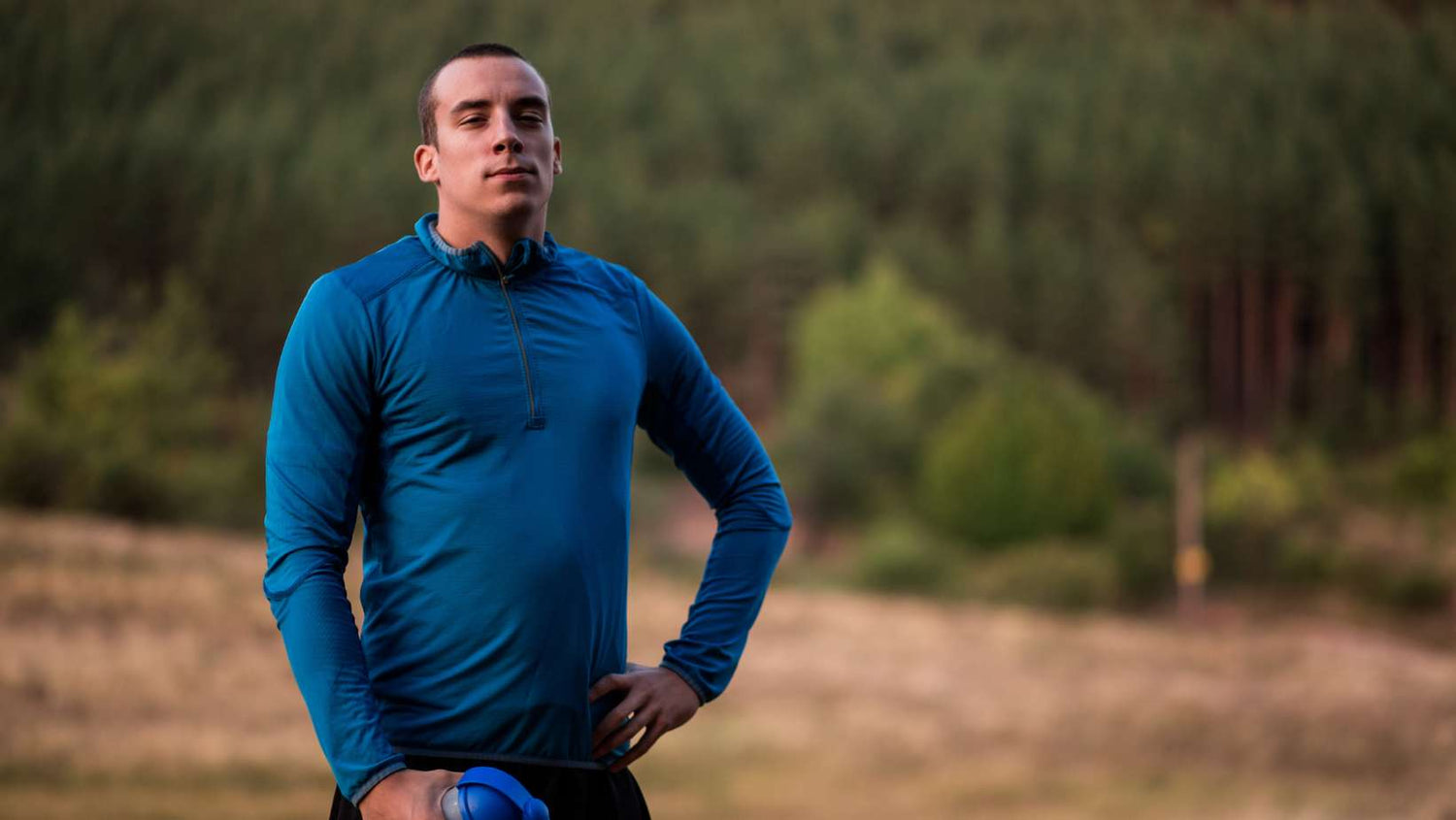 Handsome athelete man standing in natural scenery and looking at view