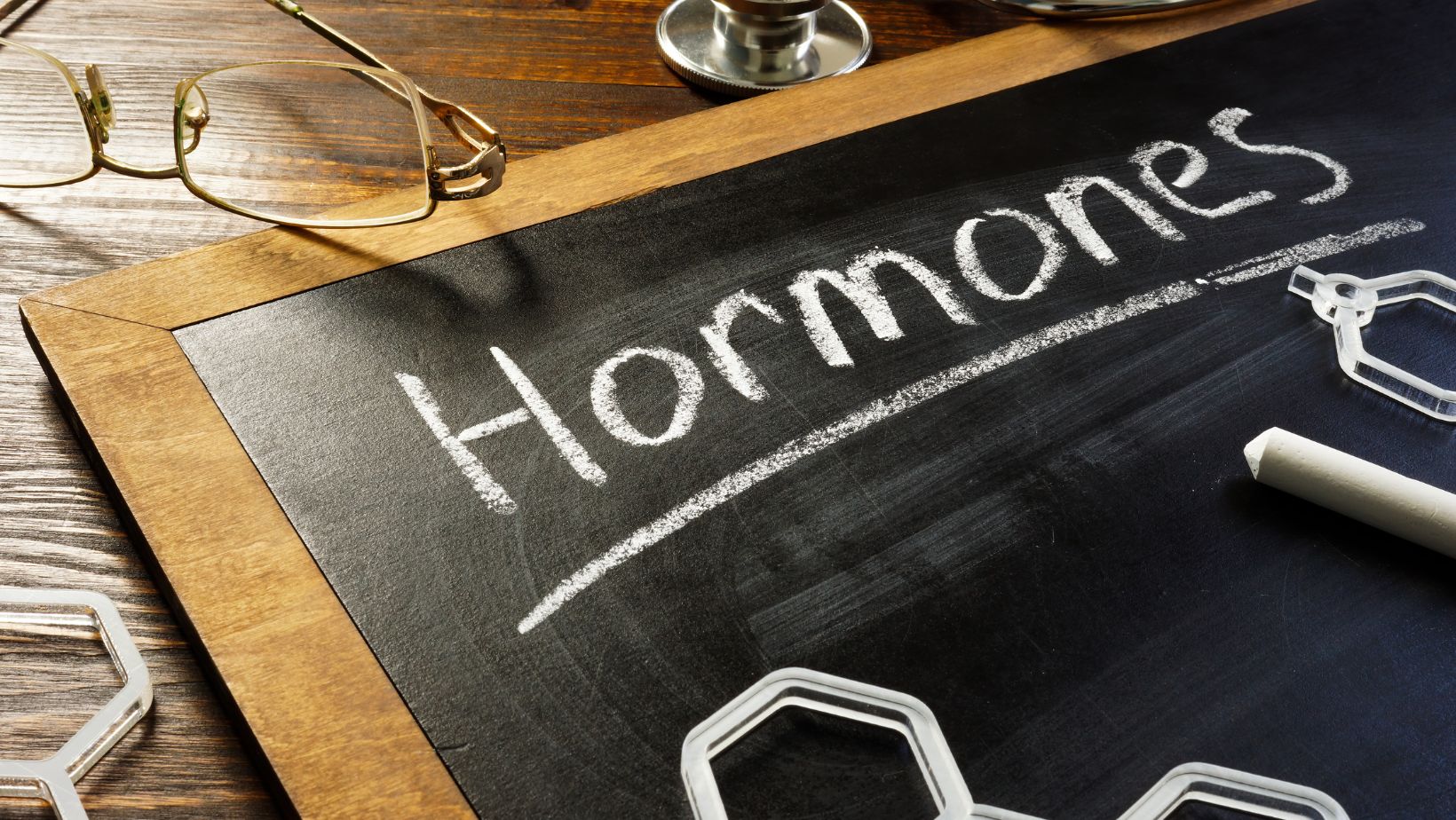 Handwritten word hormones on the blackboard and glasses