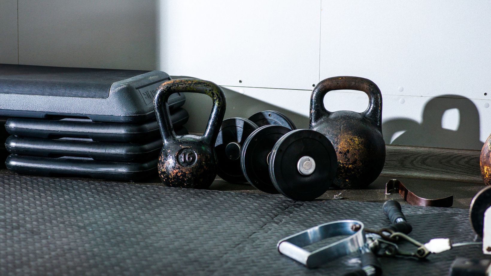 Kettle bells and dumbbells on floor near gym equipment