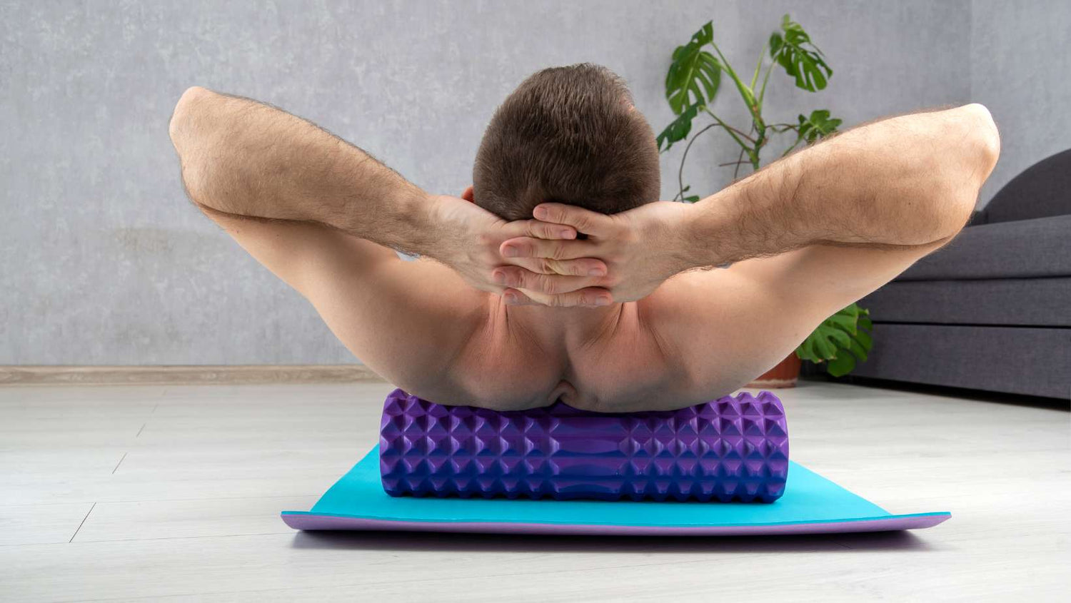 Man Doing Fascial Exercise of Back with Foam Roller. Man Performing Back Exercise on Myofascial Roller at Home