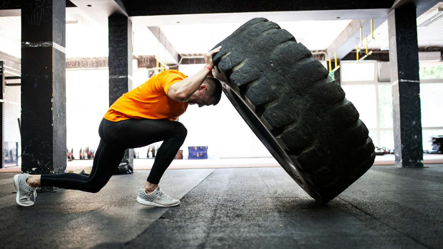 Man working out in gym, flipping a tire