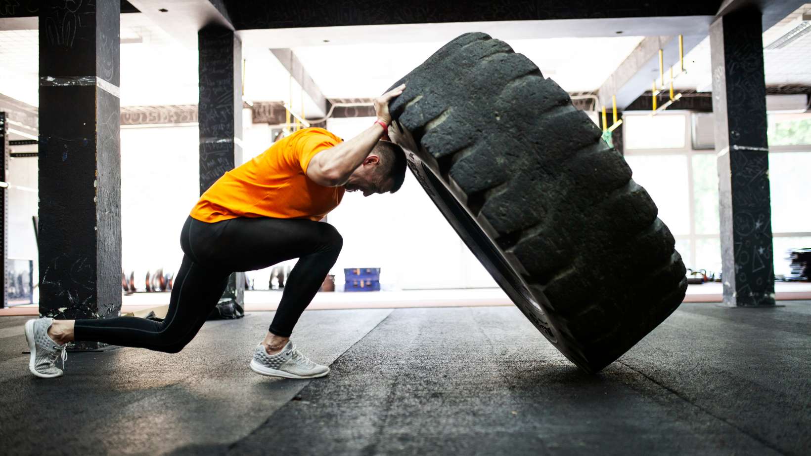 Man working out in gym, flipping a tire