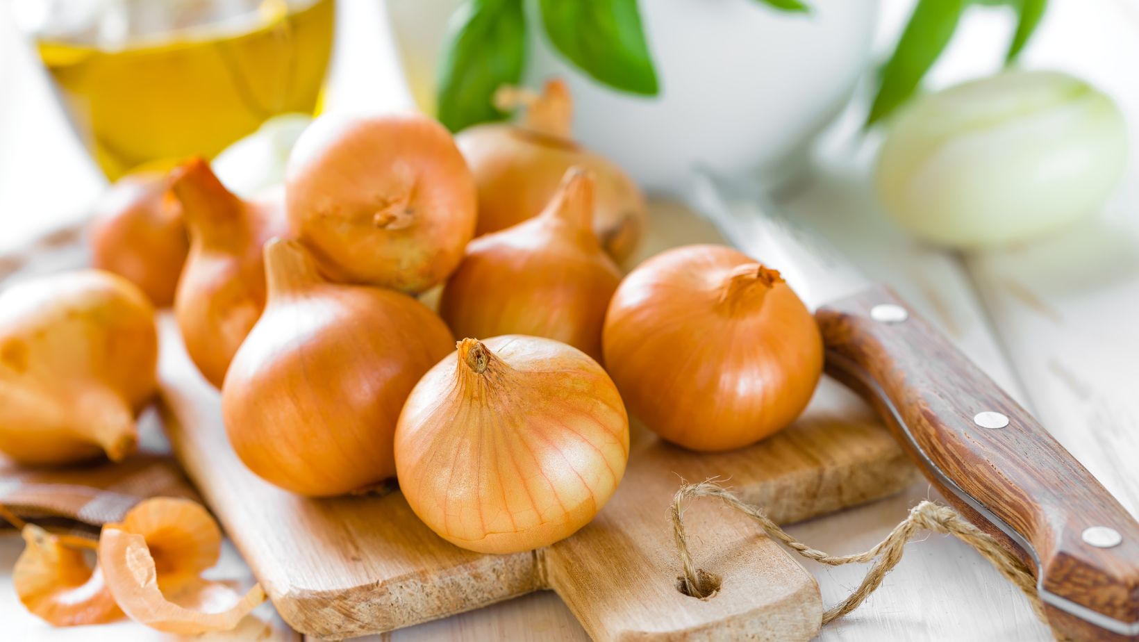 Onions on a chopping board with a knife beside