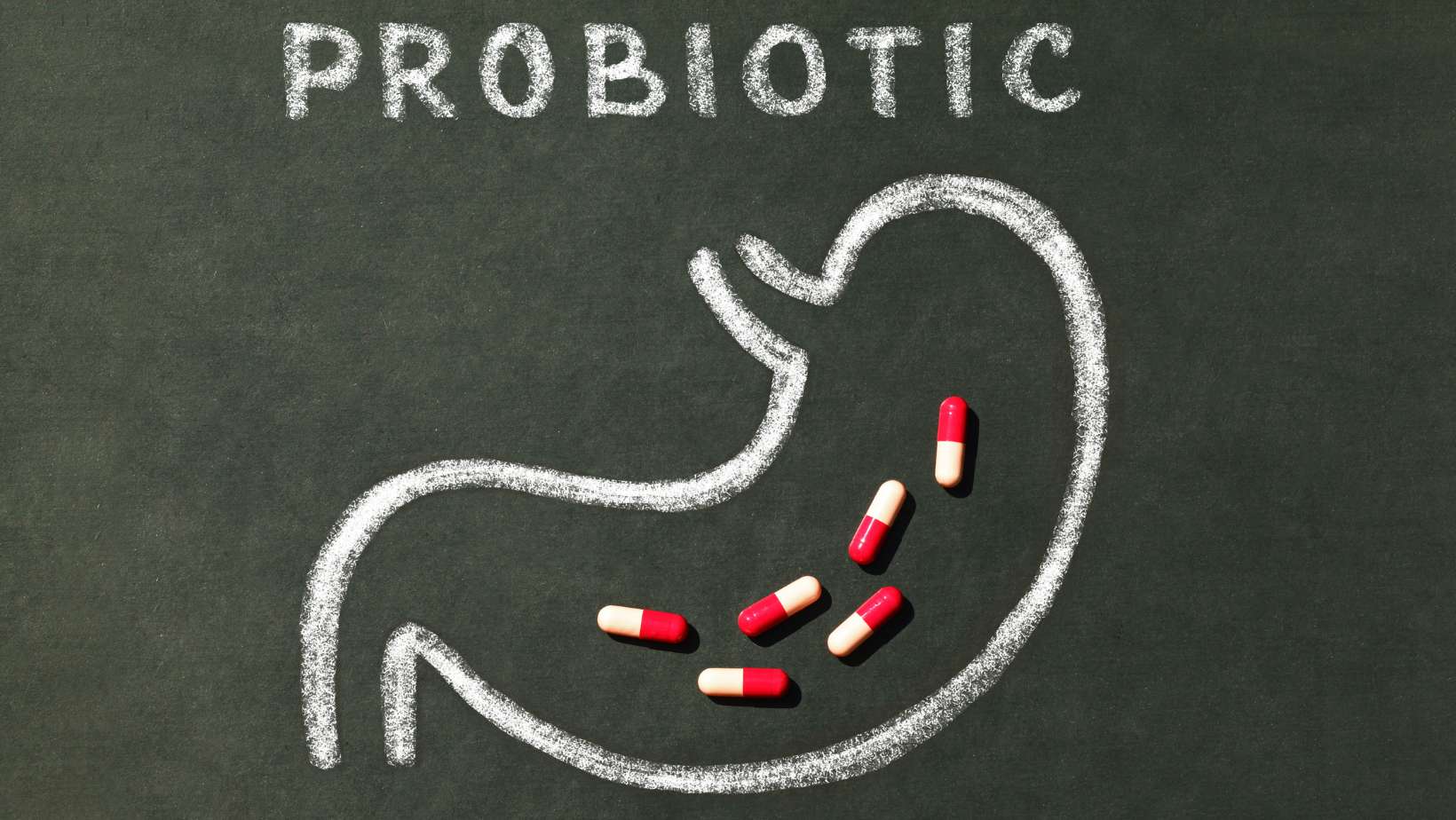 Pills in stomach contour and word Probiotics on a blackboard