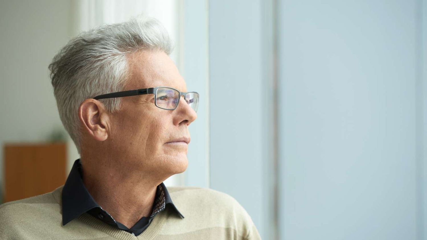 Portrait of pensive senior man looking through window