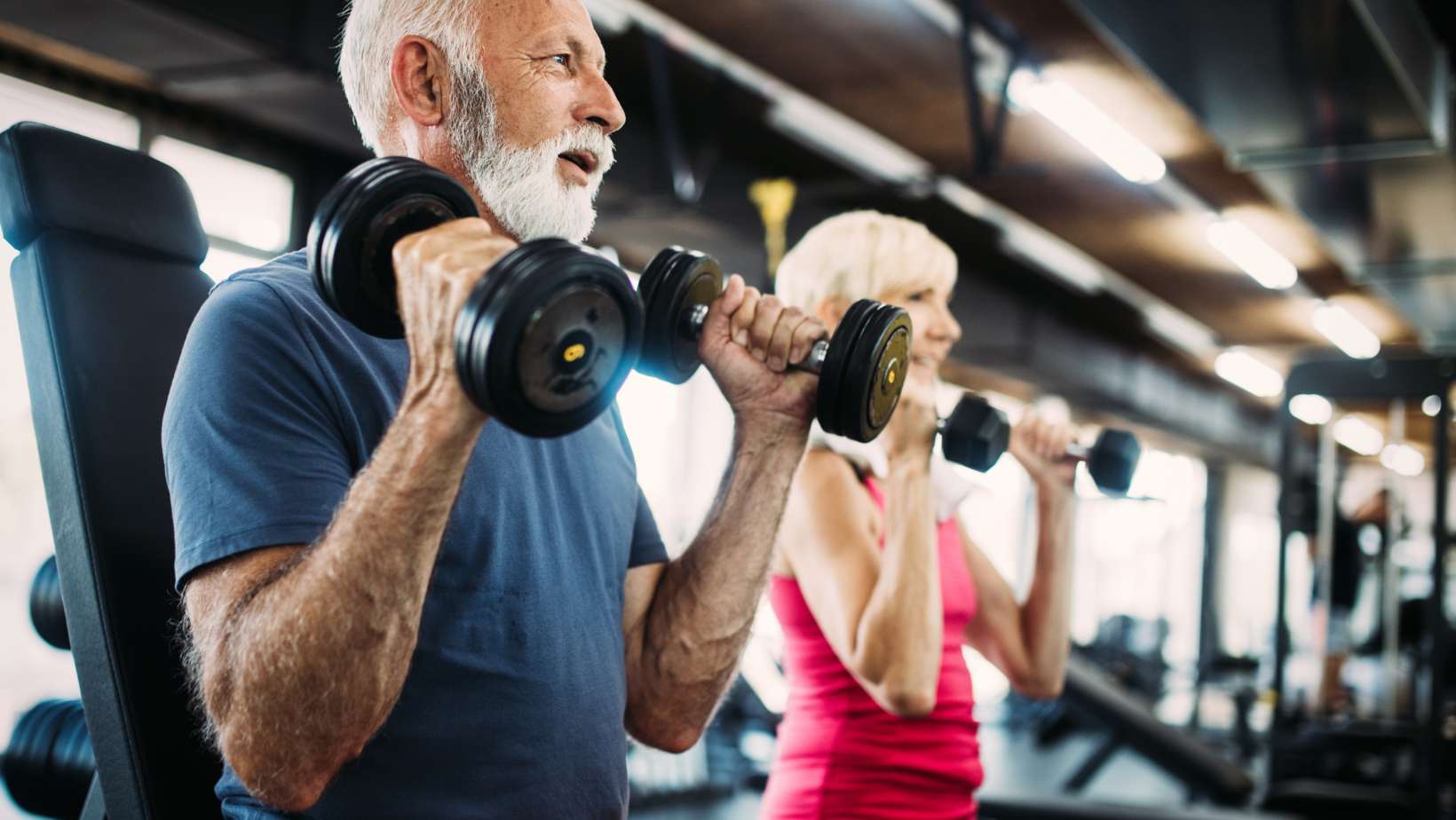 Senior fit man and woman doing exercises in gym to stay healthy
