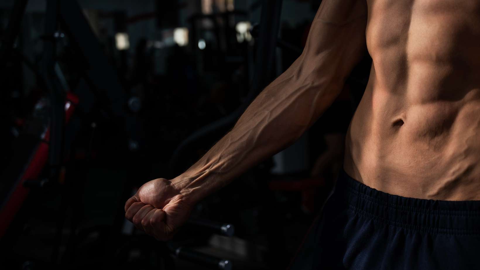 Shirtless man flexing his body in the gym