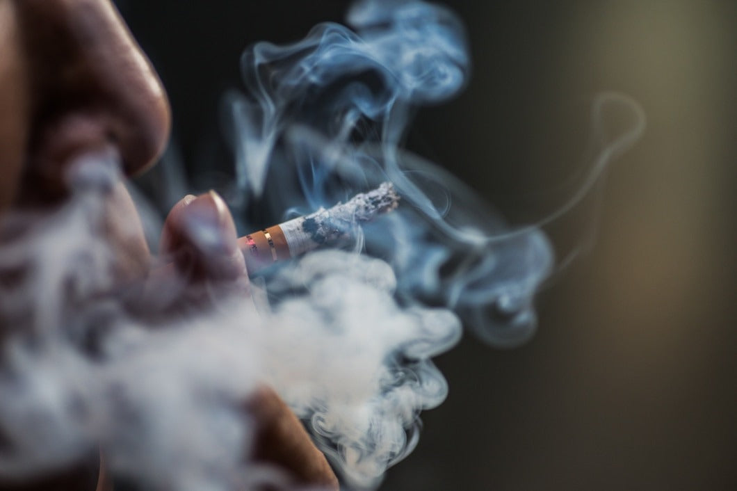 closeup shot of a person puffing on a cigarette surrounded with smoke