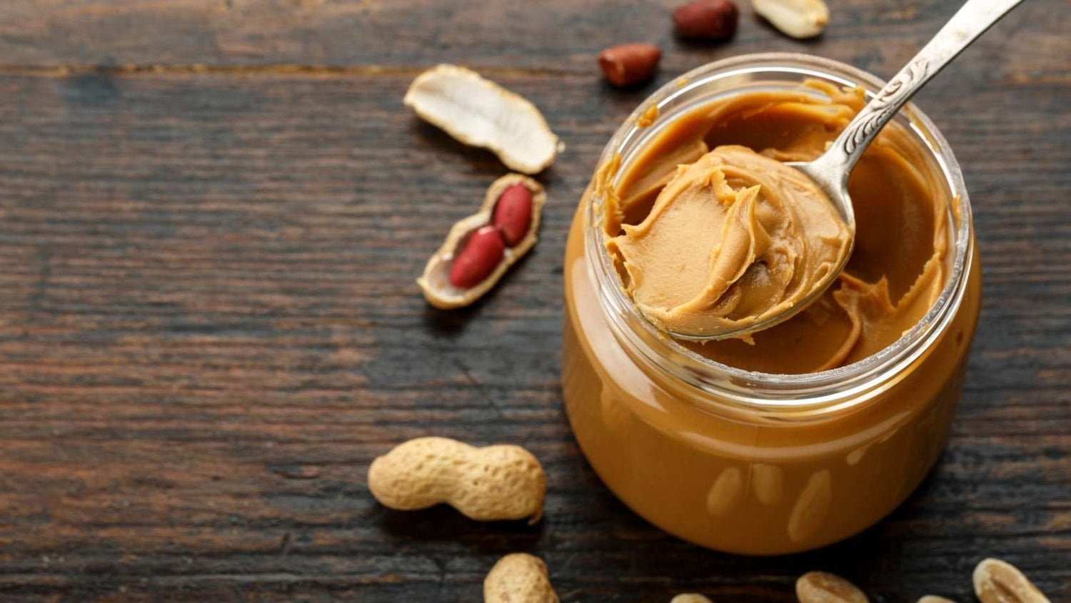 peanut paste in an open jar and peanuts